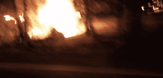 A photo from the scene of a rollover crash shows part of the crash site on fire.