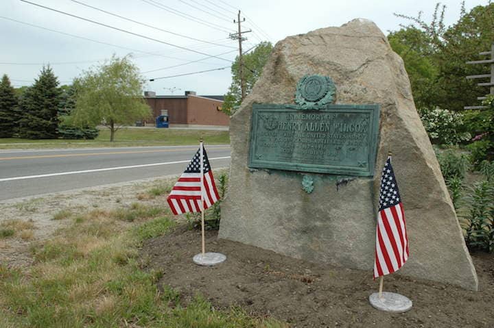 A small memorial adorned with flags alongside Warwick Avenue near Bishop Hendricken High School.