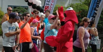 Sean Galligan high-fives runners before The 2015 RP5K .