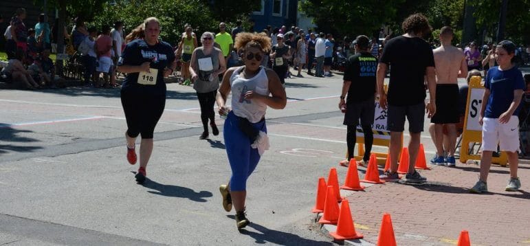 [CREDIT: Rob Borkowski] Jenarita Plante, 29, of Coventry, right, rear, rounds the corner at Rhodes Place, just behind an unidentified runner. 