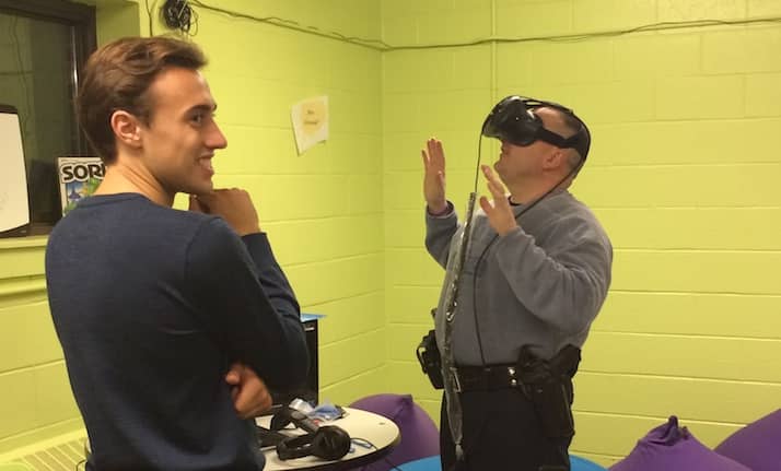 [CREDIT: Rob Borkowski] Officer Al Malucci tries out the Virtual Reality set in the game room at the The Club at Cooper Tuesday. Malucci is seeing a 3-D view of a digital mountain top patio. Supervising him for his safety is volunteer Dante Prosseda.