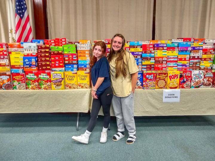 [CREDIT: Linc Smith] Emily McGuire and Emma Vernet in front of the cereal collected for the Cereal Challenge.