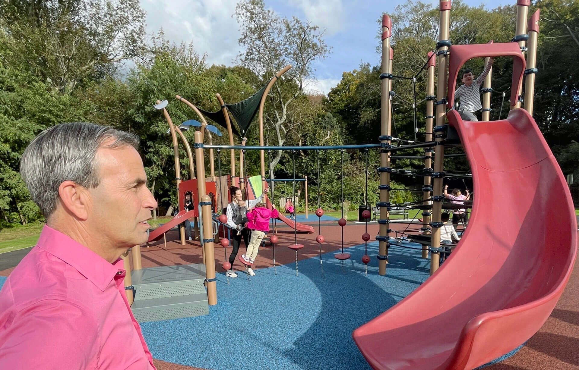 [CREDIT: Rob Borkowski] Mayor Frank Picozzi, left, and his grandson, right, top of slide, at the new Apponaug Playground Tuesday for the ribbon cutting ceremony.