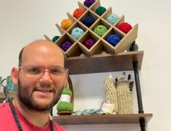 [CREDIT: Rob Borkowski] Knitting artist Robert Brosnahan sells his knit fingerless gloves, scarves and hats at Out of the Box Gallery in Jamestown, RI.