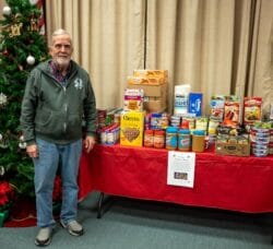 [CREDIT: Bob Mattera,President, PSRI] Lakewood Baptist and Photographic Society of RI (PSRI) member Lincoln Smith with the food soon to be delivered to West Bay Marketplace following the PSRI Christmas Food Collection for 2025.